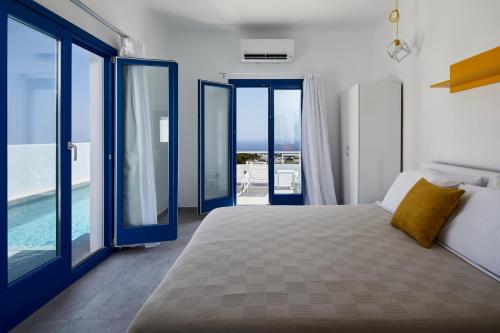 a bedroom with a bed and sliding glass doors at Thadeos Villa with private jetted Pool in Fira