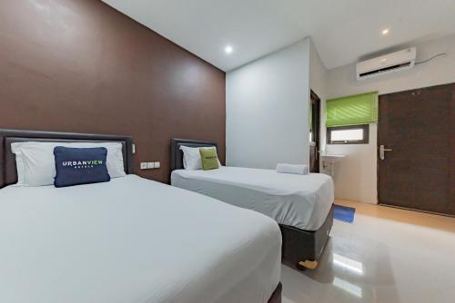 TumbangrunganにあるUrbanview Hotel Yoga Palangkaraya by RedDoorzのベッド2台とドアが備わるホテルルームです。