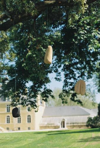 a group of hats hanging from a tree in front of a building at DOMAINE LE MEZO in Ploeren