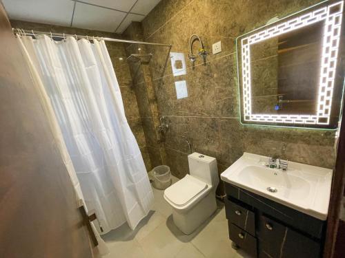 uma casa de banho com um WC, um lavatório e um espelho. em The Empire Suites em Gurgaon