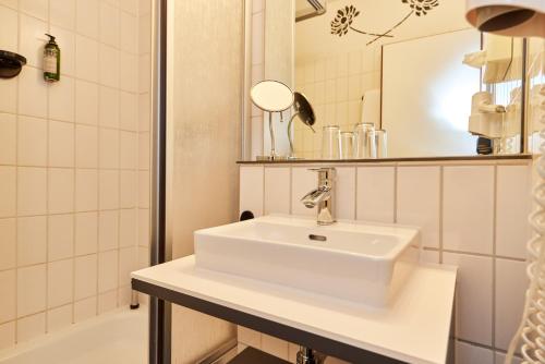 a bathroom with a sink and a mirror and a tub at Hotelpark der Westerwald Treff in Oberlahr