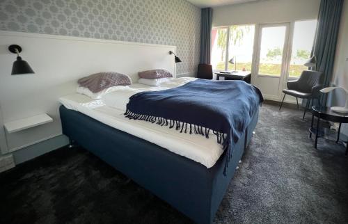 Schlafzimmer mit einem großen Bett mit blauer Decke in der Unterkunft Sallingsund Færgekro in Nykøbing Mors
