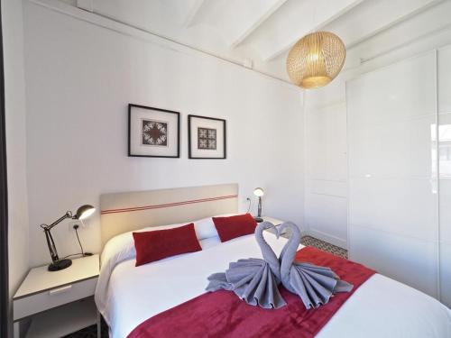 a white bedroom with a large bed with red pillows at Sunny Rooftop Apartment in Barcelona