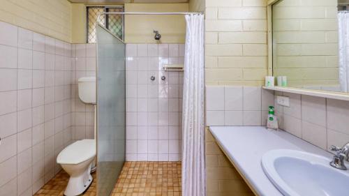 a bathroom with a shower and a toilet and a sink at Oasis Motor Inn in Broken Hill