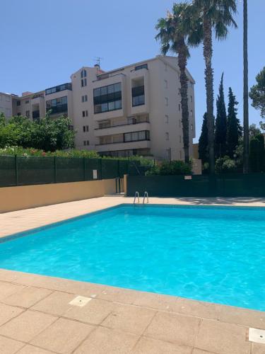 dos personas están de pie en una piscina azul en Appartement idéalement situé en Saint-Raphaël