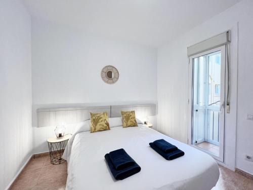 a bedroom with a large white bed with two blue pillows on it at Villa Olimpica Beach in Barcelona