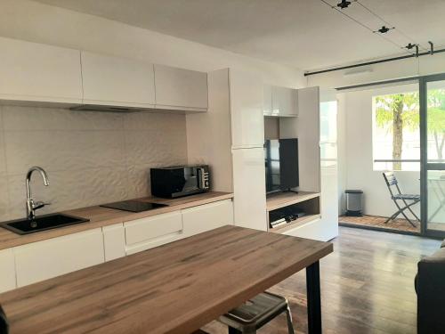 une cuisine avec des armoires blanches et une table en bois dans l'établissement Studio Calypso, à La Rochelle