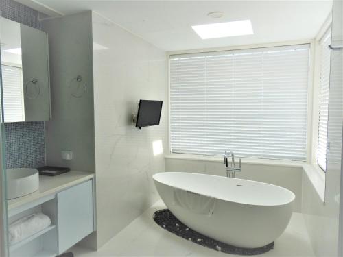 a bathroom with a large white tub and a window at Healthcare Town Resort in Seogwipo