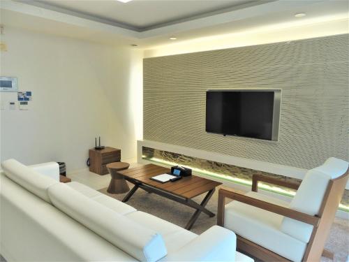 a living room with a couch and a tv on a wall at Healthcare Town Resort in Seogwipo