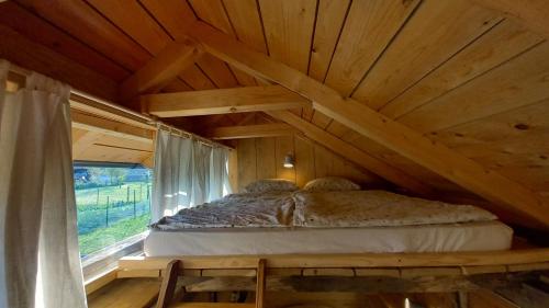 Bett in einem Holzzimmer mit Fenster in der Unterkunft Pig barn - Svinjaki 