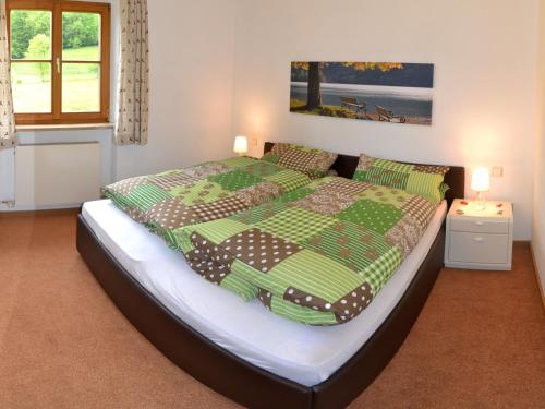 a bedroom with a large bed with a green comforter at Haus Sonnbichl in Schliersee