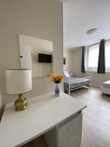 ein weißes Wohnzimmer mit einem Tisch und einer Lampe in der Unterkunft Albergo Lodrino in Villa