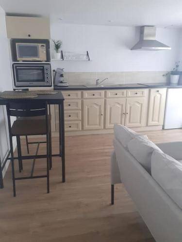cocina con mesa, microondas y sofá en Appartement neuf et cosy, en Cambo-les-Bains