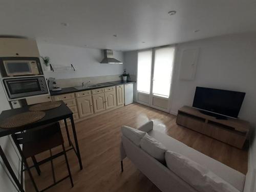 sala de estar con sofá, mesa y cocina en Appartement neuf et cosy, en Cambo-les-Bains