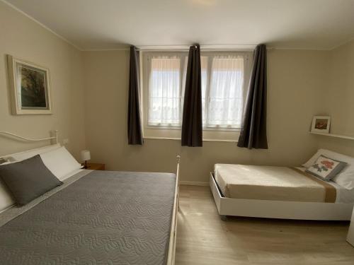 a bedroom with two beds and two windows at Albergo Lodrino in Villa