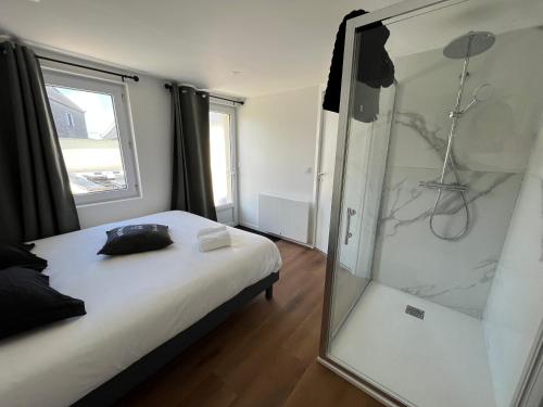 a bedroom with a shower and a bed with a glass door at Maison de charme avec jacuzzi - Bretagne / île de Batz in Île de Batz