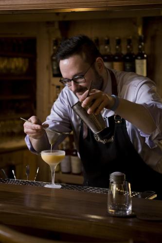 a man in an apron making a drink at a bar at Hotel Englhof in Zell am Ziller