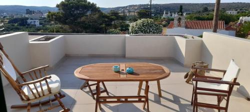 a wooden table and two chairs on a balcony at Kytherea Luxury Apartments in Livadi