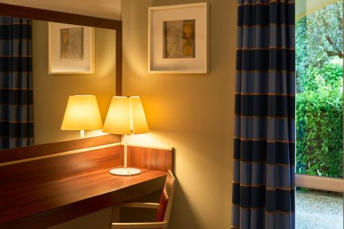 a desk with two lamps on it next to a window at Delfina Palace Hotel in Foligno