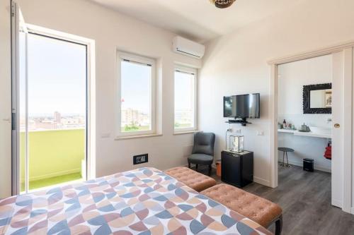 a bedroom with a bed and a tv and windows at Eleventh Floor Suites in Cagliari