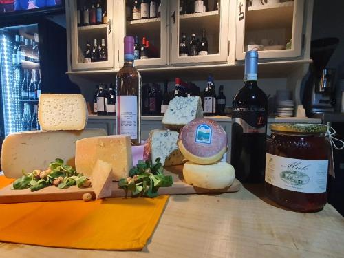 a bunch of cheese on a counter with bottles of wine at Agriturismo Cascina L'Arché in Santo Stefano Belbo