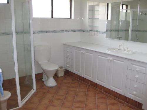 a white bathroom with a toilet and a sink at Dalmeny Shores in Dalmeny