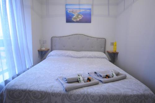 a bed with two towels and two slippers on it at Apartamento con encanto 2 hab céntrico-ayuntamiento in Santander