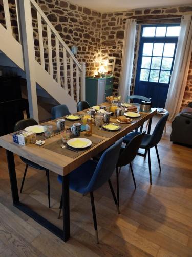 una larga mesa de madera con sillas y platos. en Chambres d'hôtes Frehel, en Fréhel
