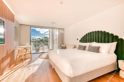 Schlafzimmer mit einem großen weißen Bett mit einem grünen Kopfteil in der Unterkunft Essence Boutique Hotel in Peregian Beach