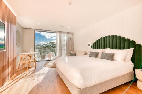 a bedroom with a large white bed with a green headboard at Essence Peregian Beach in Peregian Beach