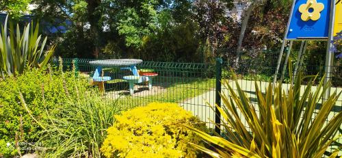a garden with a table and chairs and yellow flowers at APPARTEMENT 100 Metres de la mer in Plérin