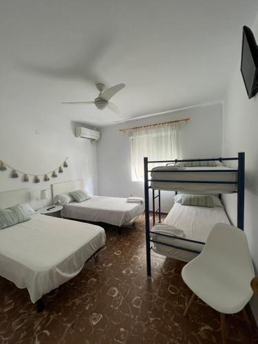 a room with three beds and a chair in it at Hostal Beni in Benicàssim