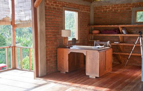 a room with a wooden desk in a brick wall at Bukit Cottage Pak Ansel in Labuan Bajo