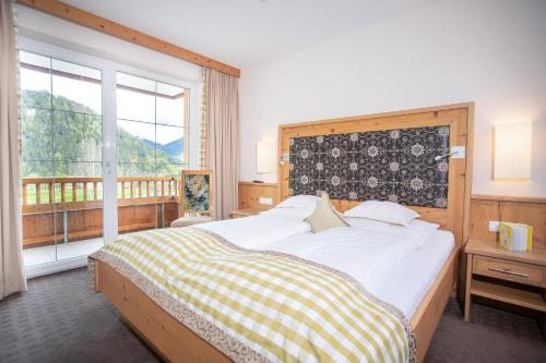 a bedroom with a large bed and a large window at Alphaus Aparthotel in Pertisau