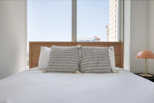 a bed with white sheets and pillows in front of a window at South Loop 1BR w gym pool nr Grant Park CHI-764 in Chicago