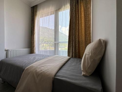 un letto in una camera da letto con una grande finestra di Olympos Likya Apart Otel a Yenbey