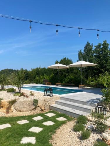 una piscina con sedie e ombrelloni di Meridiem Holiday Home in Dubrovnik region a Gruda