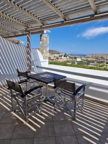 een patio met 2 stoelen en een tafel op een dak bij Harama hotel Schinoussa in Skhoinoussa