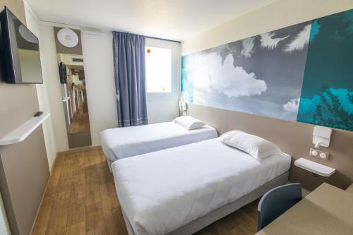 Cette chambre comprend 2 lits et une table. dans l'établissement Kyriad Direct - Bourg les Valence, à Bourg-lès-Valence