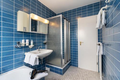 a blue tiled bathroom with a sink and a shower at Michels Ferienwohnung Schöne Aussicht in Morsum
