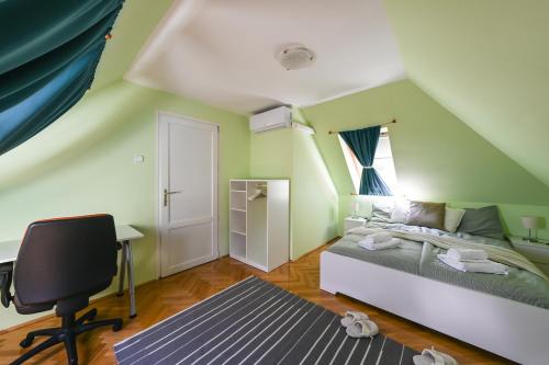 1 dormitorio con cama, escritorio y silla en Kozmáry Vendégház, en Mátrafüred