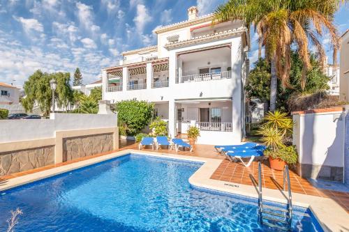 uma villa com piscina em frente a uma casa em Villa Amapolas em Nerja