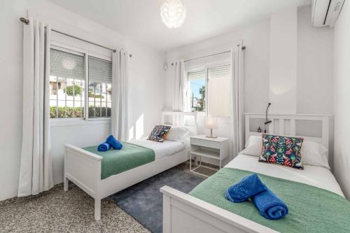 um quarto branco com 2 camas e uma janela em Villa Amapolas em Nerja