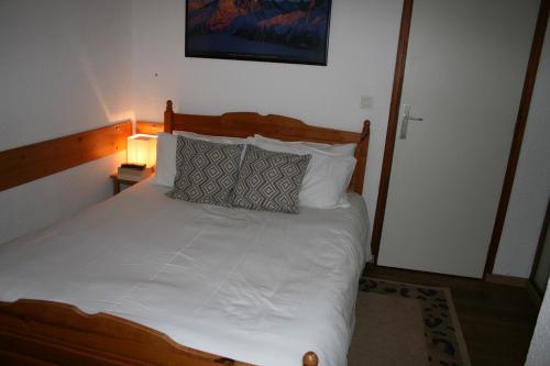 ein Bett mit weißer Bettwäsche und Kissen in einem Schlafzimmer in der Unterkunft Ski in and Out 2-Bed Apartment in Meribel in Les Allues