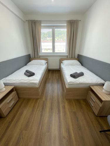 two beds in a room with wooden floors and windows at Ubytovanie HAMAR 17 in Banská Bystrica