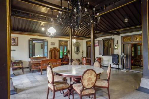 a dining room with a table and chairs and a chandelier at Cakra Homestay Solo Mitra RedDoorz in Solo