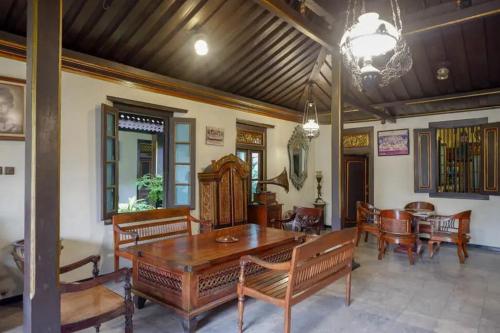 a dining room with a wooden table and chairs at Cakra Homestay Solo Mitra RedDoorz in Solo