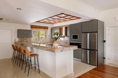 a kitchen with a large island with bar stools at Bello Blu Luxury Villa in Asgourou
