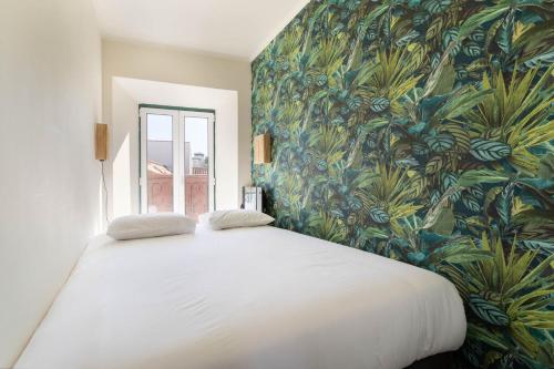 Un dormitorio con una cama blanca con papel pintado tropical. en Vila Santa Marinha, en Lisboa