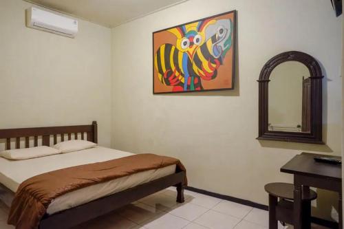una camera da letto con un letto e un dipinto sul muro di Cakra Homestay Solo Mitra RedDoorz a Solo